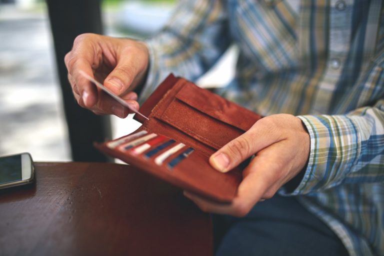 Man holding brown wallet to take out cash and credit card